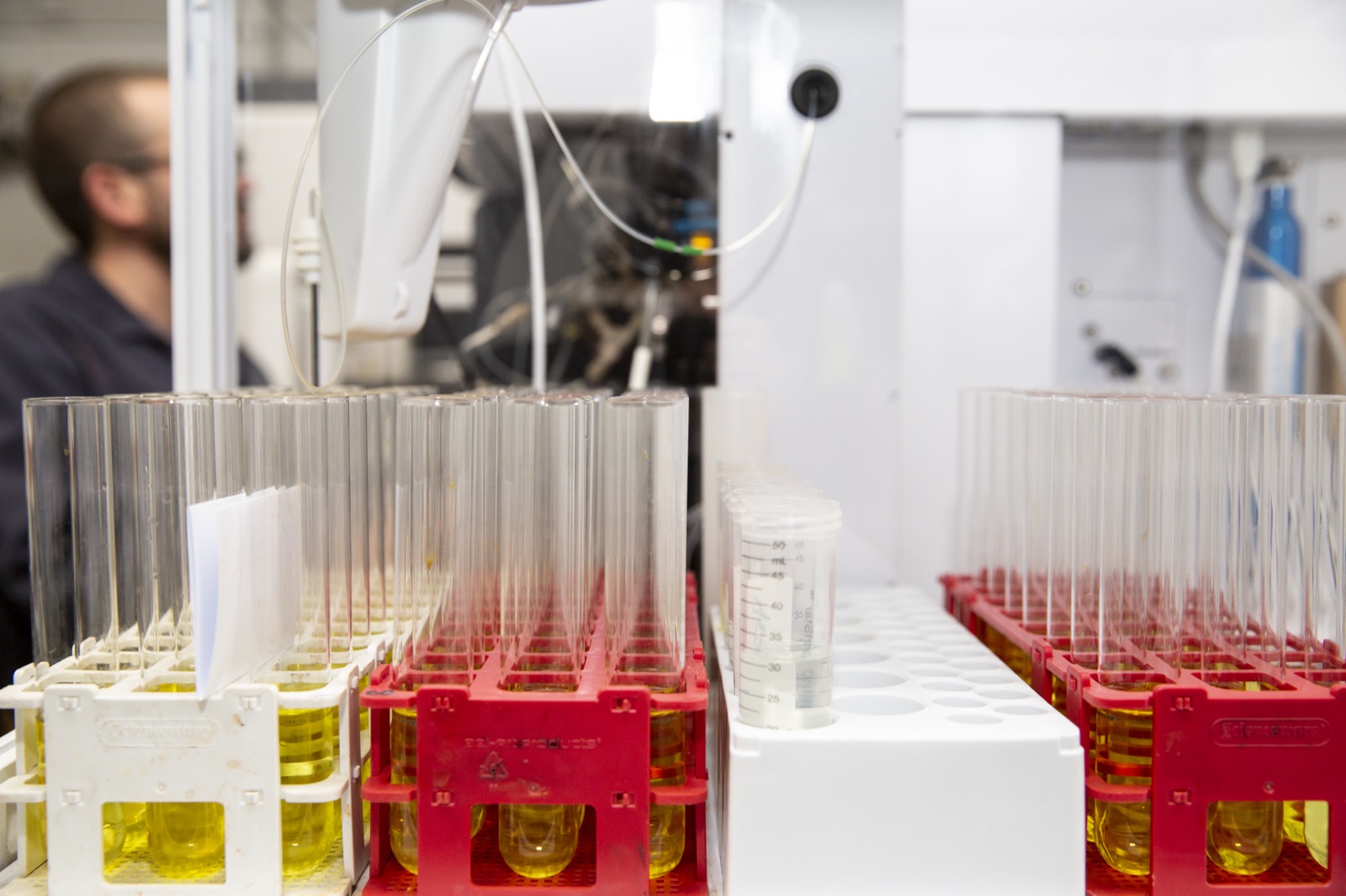 Racks of digestion test tubes filled with clear-to-amber solution ready for ICP-OES analysis