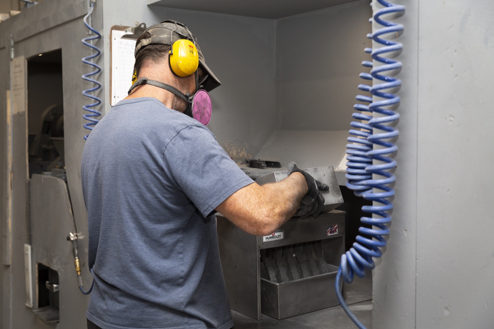 A worker in protective equipment operating a jaw crusher in the Eastern Analytical crushing room